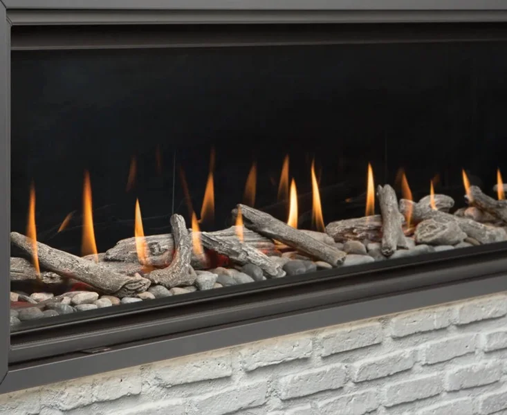 a gas fireplace with driftwood logs and stones inside